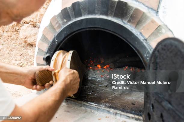 Artisan Woodfired Oven And Mans Hands Blowing The Embers With A Bellows Stock Photo - Download Image Now