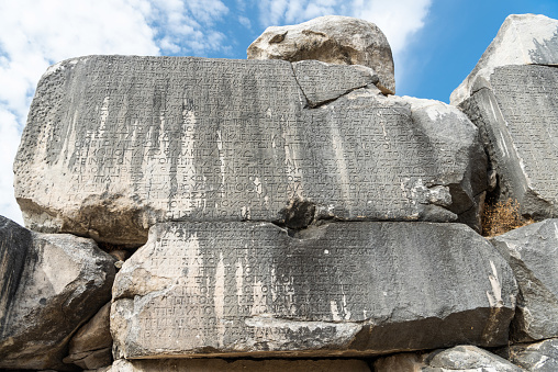 Eskihisar, Mugla, Turkey - October 7, 2020. Ancient Greek inscriptions on the walls of council house Bouleuterion of Stratonikeia ancient site in Mugla, Turkey. These inscriptions list the names and durations of the months in the calendar made by Menippos. Stratonikeia was one of the most important towns in the interior of ancient Caria.
