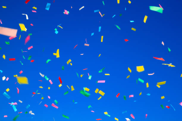 istock multicolored confetti on clear blue sky background. Concept of h 1342340599