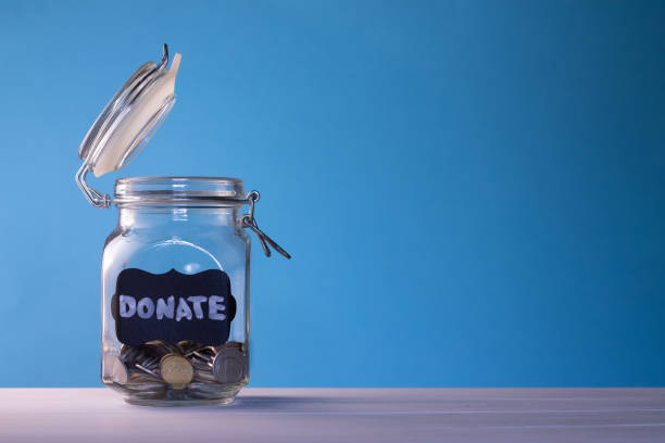 Glass jar with coins with chalk tag Donate on a blue background. Donation and charity concept. Copy space. stock photo