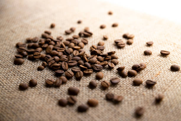 grains de café sur fond de tissu de lin - coffee sack bag espresso photos et images de collection