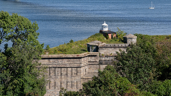 The Fort Wadsworth Light, a squat red brick lighthouse with a white lantern room, stands atop Battery Weed barely north of the western tower of the Verrazano-Narrows Bridge that spans the entrance to New York harbor.