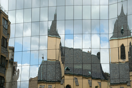 Gothic Arcitecture reflecting in the mirror glass facade of a modern building. Old and new architecture concept