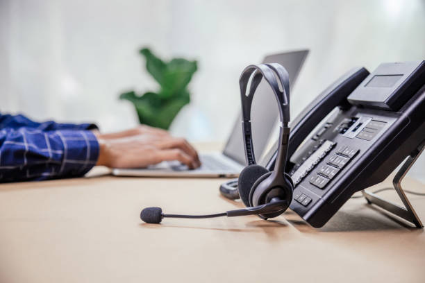 Communication support, call center and customer service help desk. telephone devices with VOIP headset in office.Customer service support (call center) concept. Communication support, call center and customer service help desk. telephone devices with VOIP headset in office.Customer service support (call center) concept. voip stock pictures, royalty-free photos & images