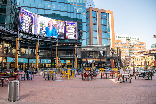 Denver, Colorado - August 28, 2021: View of McGregor Square and it's giant screen tv, where sports and movies are played with outdoor seating for bars and restaurants.