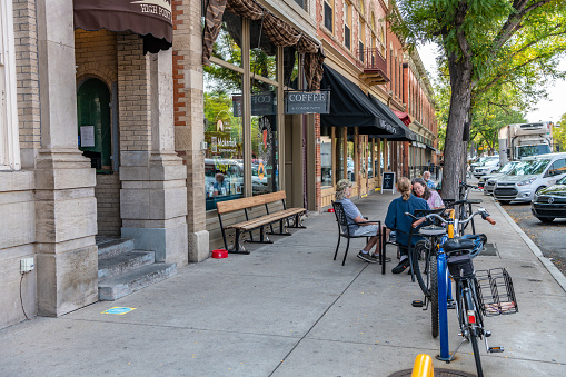 Fort Collins, CO - August 30,2021: People dine outdoors on a sidewalk patio downtown, in the Old Town area along College Avenue.