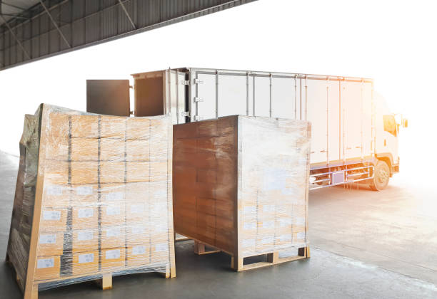 istock Package Boxes Wrapped Plastic Film on Pallets Loading with Shipping Cargo Container. Truck Parked Loading at Dock Warehouse. Delivery. Warehouse Logistics. Cargo Freight Truck Transportation. 1342383754