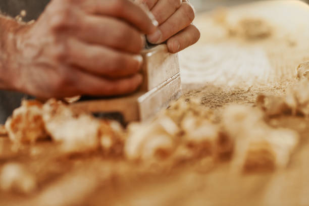 istock Carpenter using a planer to smooth the surface of wood 1342388821
