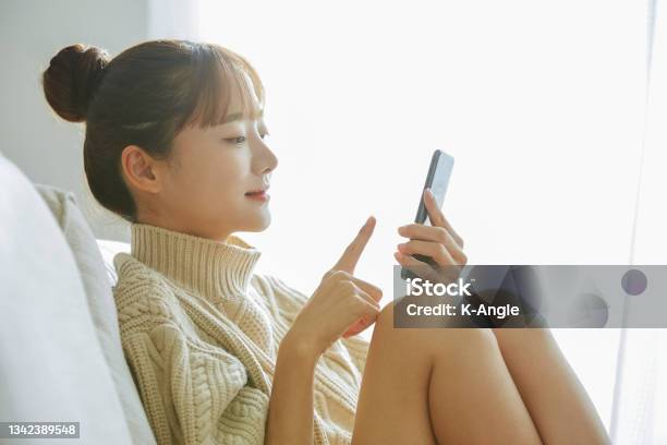 A Young Asian Woman Operating A Phone At Home Stock Photo - Download Image Now - Women, Smart Phone, Japanese Ethnicity