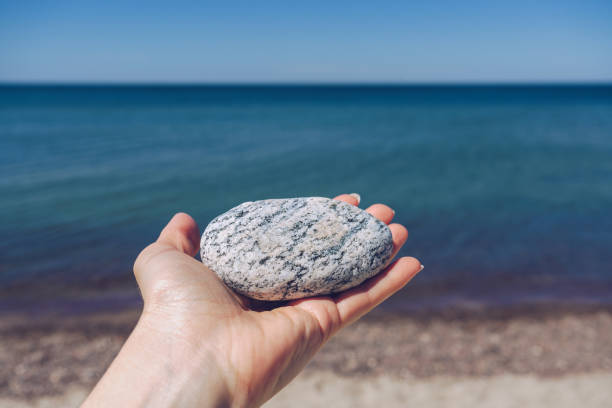 istock rounded boulder in womans hand on sunny day with vast seascape on background 1342390769