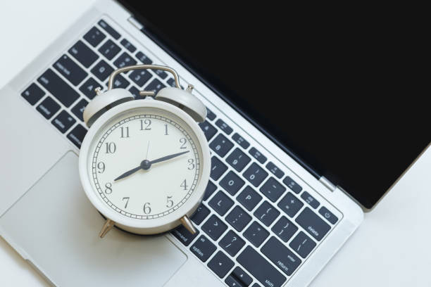 istock Alarm clock on computer laptop on table. business time working at workspace. 1342391487