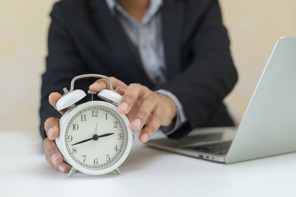 istock Businessman holding analog white alarm clock for setting time at office table. working time concept. 1342391641