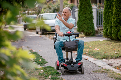 Senior man in electric wheelchair enjoys in  neighborhood