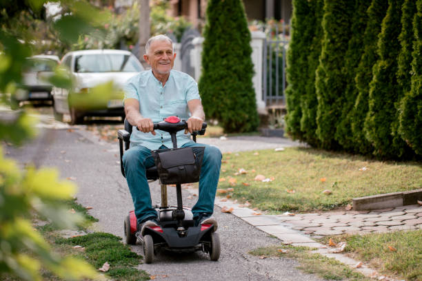 hombre mayor conduce silla de ruedas eléctrica - ciclomotor fotografías e imágenes de stock