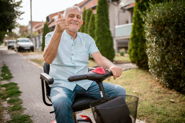Portrait of happy senior man with a disability in electric wheelchair scooter stock photo