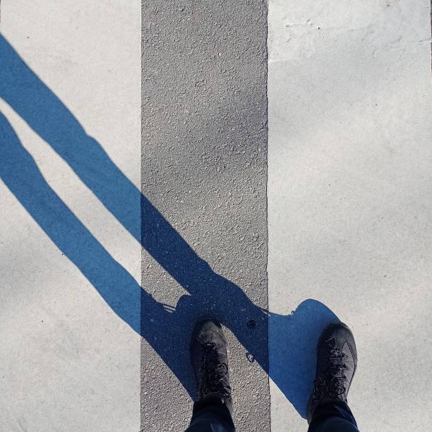istock Low Sectio Of Legs And Shadow On Zebra Cross Walk. Abstract Conceptual Image. 1342399807