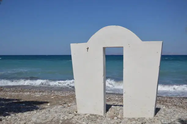 Photo of An arch standing on the pebble coast of the Aegean Sea in the village of Theologos in the Rhodes, Greece