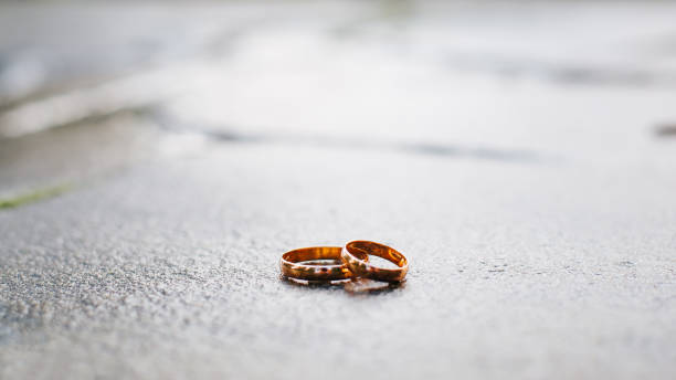 istock Two gold wedding rings on a stone surface, frontal view. Wedding, marriage, love concept. Selective focus on jewelry 1342405449
