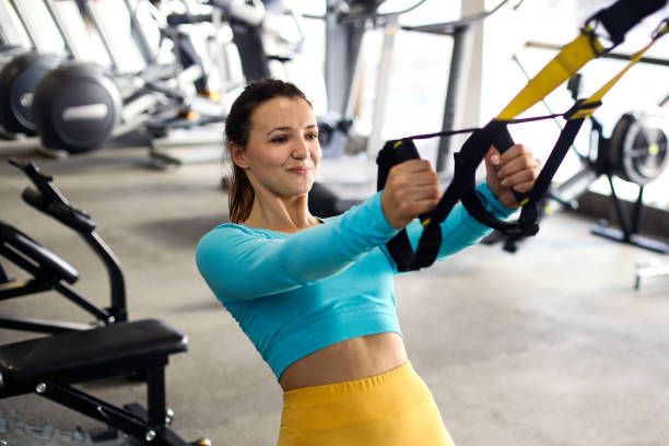 Suspension training Young woman exercising on suspension straps in a gym ripl fitness