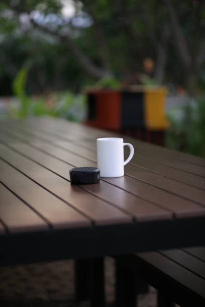 mise au point sélective d’un café mug blanc et d’un petit haut-parleur sur la table en bois dans le jardin - cafe table outdoors speaker photos et images de collection