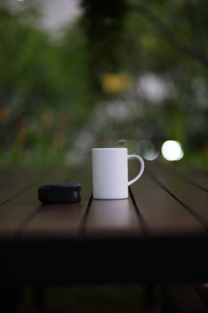 cus d’une tasse de café blanc et un petit haut-parleur sur la table en bois - cafe table outdoors speaker photos et images de collection