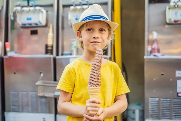 Photo of Little tourist boy eating 32 cm ice cream. 1 foot long ice cream. Long ice cream is a popular tourist attraction in Korea. Travel to Korea concept. Traveling with children concept