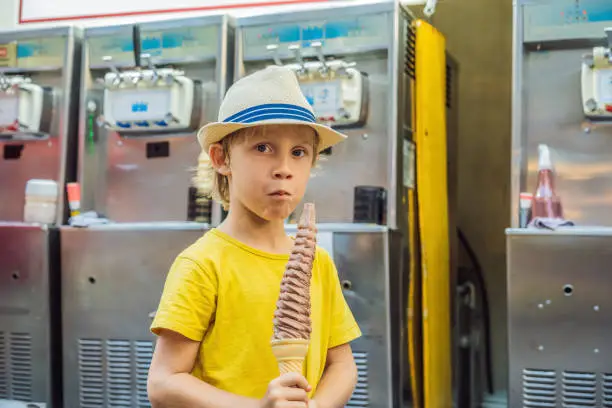 Photo of Little tourist boy eating 32 cm ice cream. 1 foot long ice cream. Long ice cream is a popular tourist attraction in Korea. Travel to Korea concept. Traveling with children concept