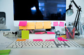 Messy workstation in office with sticky notes on computer monitor