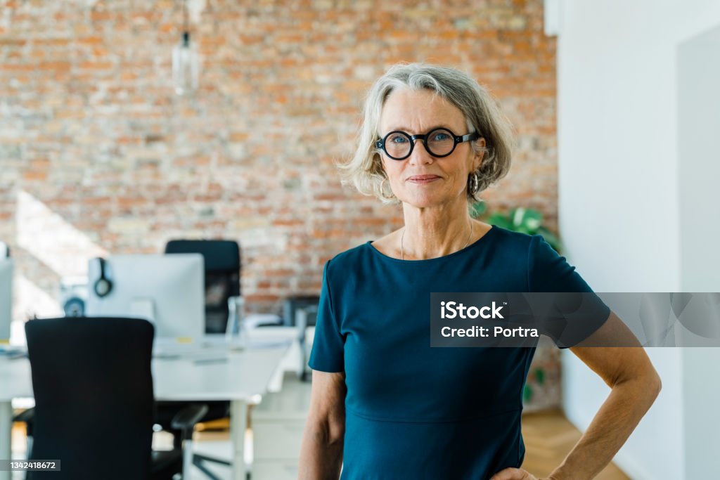 Portrait of a senior businesswoman standing in office Portrait of a senior woman standing in office. Female entrepreneur with short hair and business casuals looking at camera. Senior Adult Stock Photo