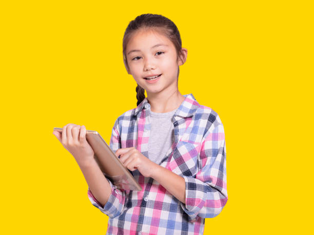 Happy student girl using tablet.Isolated on yellow background. stock photo