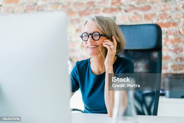 Senior Businesswoman At Her Desk Using Cell Phone Stock Photo - Download Image Now - Office, Women, Using Phone