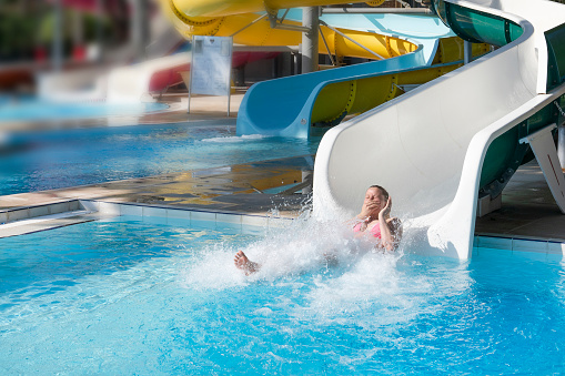 water slides, a woman with splashes and laughter plops into the water, summer entertainment on vacation at the hotel.