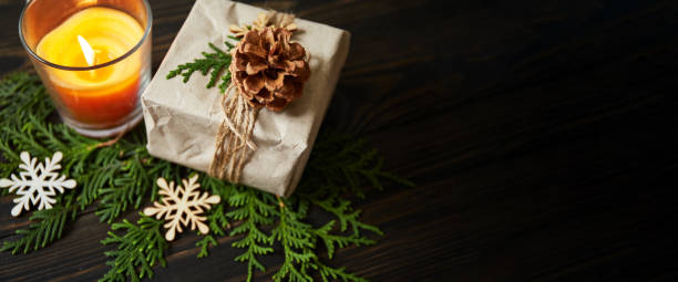 istock Zero Waste Christmas concept. Eco friendly Christmas composition with gift box in craft reusable paper, natural decor and candle on wooden background. Banner with copy space 1342428558