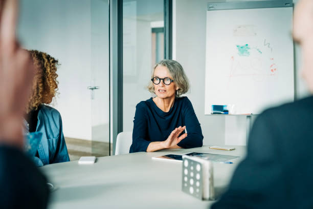 starsza bizneswoman planują z zespołem na spotkaniu - occupation togetherness meeting board room zdjęcia i obrazy z banku zdjęć