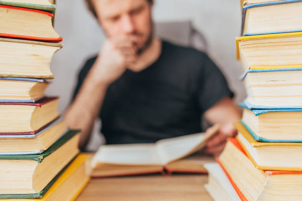 istock Two stacks of old books in color bindings - a man reading 1342429255