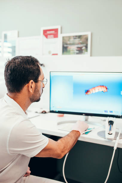 medico dentista su un computer modella la mascella per sviluppare la forma di un impianto dentale - laboratory dentures dental hygiene human teeth foto e immagini stock