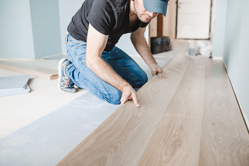 Close-up of the work of a master floating flooring installation - installing laminate on the floor - male hands during work