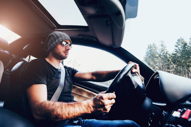 un hombre con gafas y una camiseta negra conduce un coche - street racing fotografías e imágenes de stock