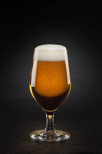 istock Mug with fresh beer with cap of foam on a black. 1342435289