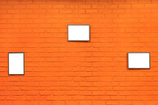 orange brick wall with gray picture frames as background