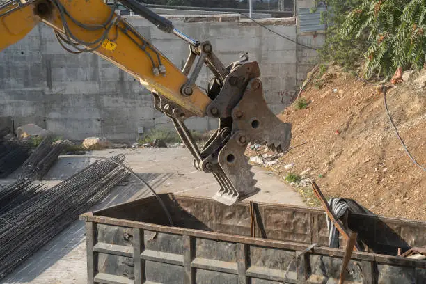 Demolition waste disposal using an excavator with a hydraulic grapple attachment.
