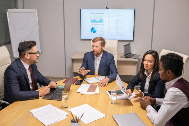 istock Two businessmen consulting about speech points while two intercultural colleagues discussing papers 1342438555