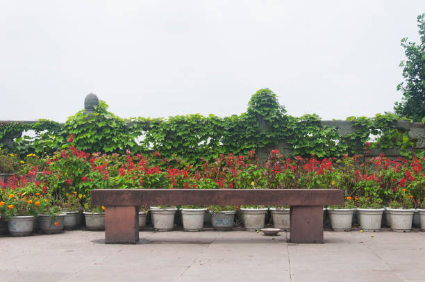 a stone bench with potted plants against a railing and overcast sky on top of Mount Wuyou in leshan china sichuan province.