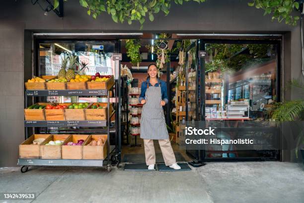 Happy Woman Working At A Local Food Market And Standing At The Door Waiting For Clients Stock Photo - Download Image Now