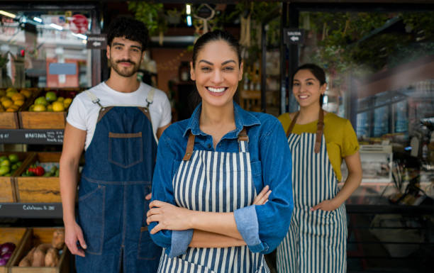 Woman leading a group of salespersons working at a food market Latin American woman leading a group of salespersons working at a local food market - small business concepts market vendor photos stock pictures, royalty-free photos & images
