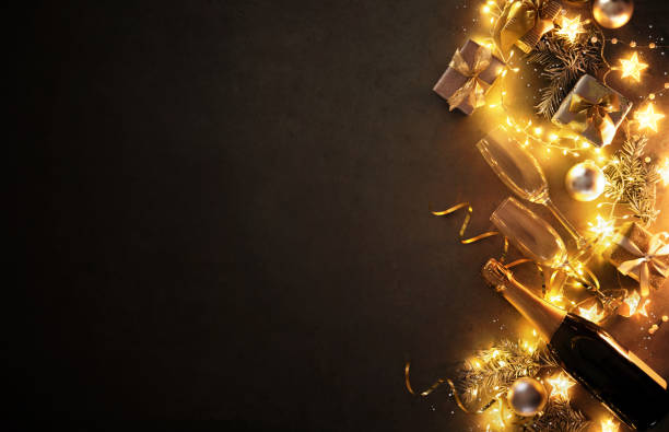 New Years Eve holiday background with fir branches, champagne bottle, christmas balls, gift box and lights stock photo