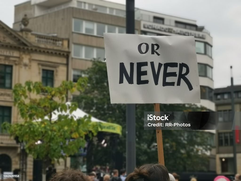 Citizens displaying their politicial demand to act now or never during green demo Mobile shot Display politics now or never Climate Justice Stock Photo