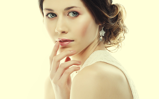jewelry, luxury, wedding and people concept: close up of beautiful woman wearing shiny diamond earrings