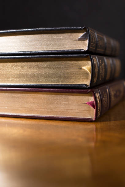 istock Stack of  beautiful leather bound books.  Highly polished wood table.  Black background.  Satin ribbon bookmarks.  Room for copy. 1342444639