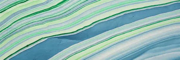 background of handmade Thai marbled mulberry paper in green and blue with flowing pattern, panoramic web banner